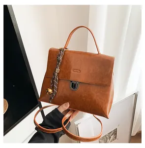 Detail der braunen Vintage-Handtasche mit Metallverschluss und böhmischem Quastenanhänger