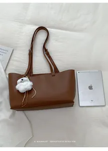 Detailed top view of large caramel brown PU leather tote bag with white plush bear charm
