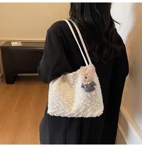 Detail of white faux fur tote bag with leather straps and a cute brown bear charm
