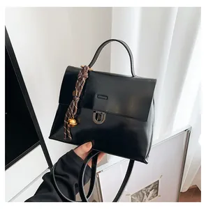 Detail einer schwarzen Lackleder-Tasche mit Silberschnalle und dekorativem Glöckchen