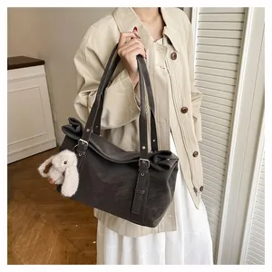 Close-up of deep brown vintage tote with matte texture and plush bunny charm