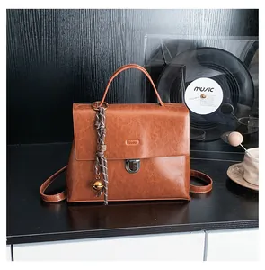 Detailansicht der braunen Vintage-Handtasche mit Metallschloss und Glockenanhänger