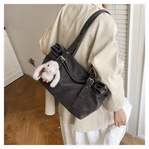 Detail of dark grey frosted shoulder bag with a cute plush rabbit charm on the strap