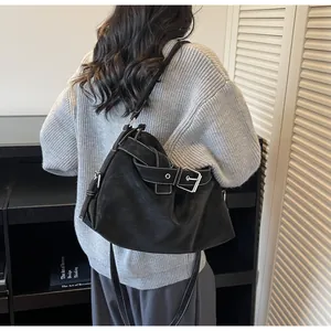 Détail d'un sac hobo noir avec surpiqûres blanches et boucle argentée sur un mannequin