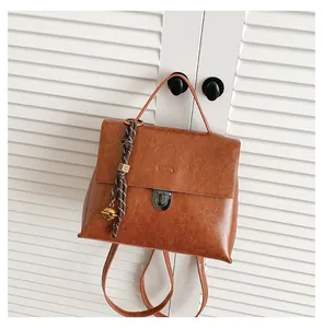 Detailansicht eines braunen Vintage-Lederrucksacks mit Drehverschluss und gewebtem Anhänger