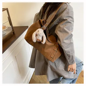 Close-up of vintage brown shoulder bag with metal buckle and plush bunny charm detail