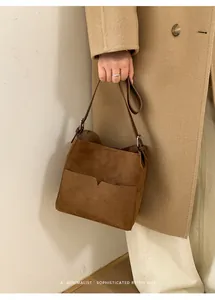 Détail du sac seau minimaliste en daim marron avec poche frontale et boucle en métal argenté