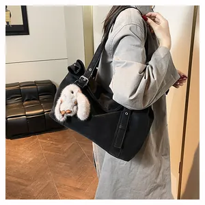 Detail of black matte leather tote bag with white plush rabbit pendant and silver buckle