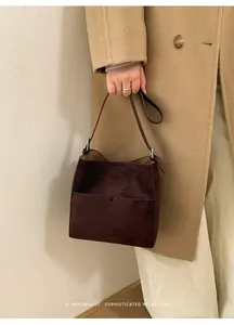 Détail du sac seau en daim marron foncé avec poche en V et boucle en métal argenté