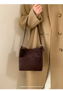 Détail du sac seau en daim marron foncé avec poche en V et bandoulière en cuir