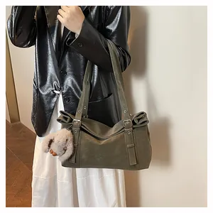 Detail of olive green matte tote bag with eyelet straps and plush rabbit charm