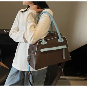 Detailed view of color-block tote bag with blue trim and adjustable fabric shoulder strap
