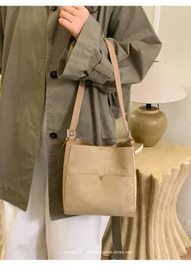 Sac seau chic en daim kaki porté avec un trench olive dans un décor rétro raffiné