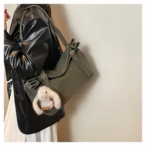 Close-up of olive green matte shoulder bag with vintage buckle and plush bunny charm