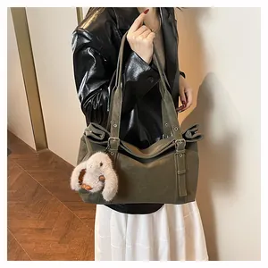 Detail of olive green faux suede tote bag with metal eyelets and plush bunny charm