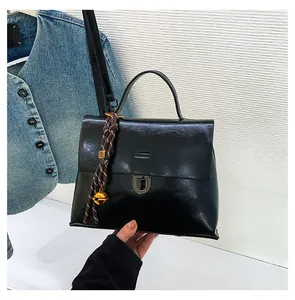 Detailaufnahme der schwarzen Lackledertasche mit silbernem Schloss und Glockenanhänger