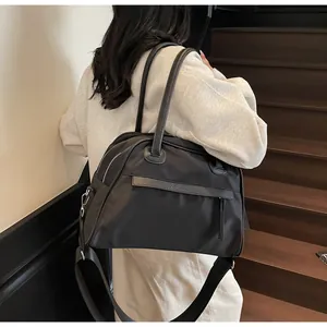 Close-up of a large black nylon tote bag worn over the shoulder with wide fabric strap