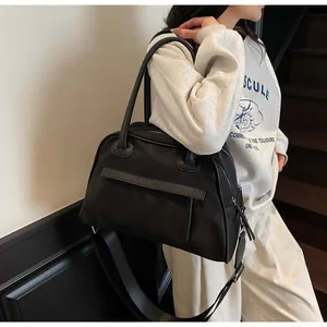 Model showing large black nylon tote bag with leather trim and adjustable shoulder strap