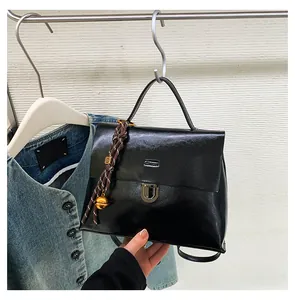 Detail der schwarzen glänzenden Handtasche mit silbernem Drehverschluss und Anhänger