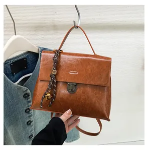 Detailansicht der braunen Vintage-Ledertasche mit Metallschnalle und Glocken-Anhänger