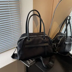 Minimalist black tote bag in durable nylon and leather trim with wide shoulder strap