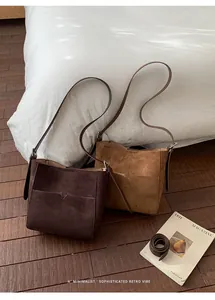 Sacs seaux marron et beige avec poches en V sur plancher en bois et literie blanche