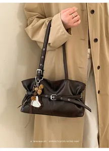 Détail d'un sac à main rétro en cuir café noir avec boucle en métal et breloque cœur