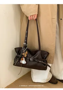 Détail du sac bandoulière rétro en cuir marron foncé avec boucles et breloque miroir cœur