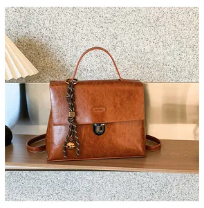 Detailansicht der braunen Lederhandtasche mit Metallschloss und gewebtem Anhänger