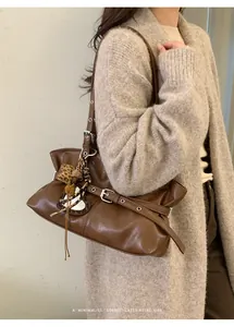 Détail d'un sac à bandoulière marron vintage avec breloque cœur léopard et boucles