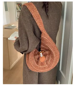 Detail of caramel knitted crescent bag with wood toggle button and beige stripes texture