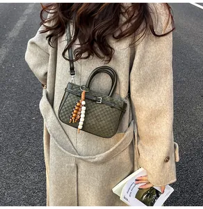 Detail view of olive green waffle pattern crossbody bag with vintage beaded charm