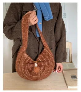 Detail of a brown knitted hobo bag showing crochet texture and a wooden toggle closure