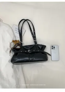 Détail du sac à épaule rétro noir avec œillets argentés et breloque cœur léopard