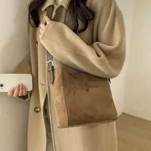 Sac seau en daim marron avec bandoulière réglable, porté en style minimaliste croisé