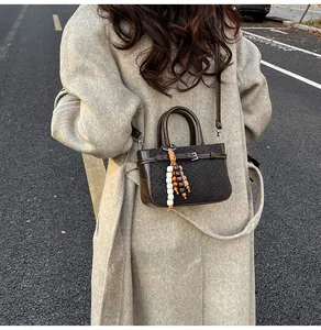 Outdoor shot of a mini dark checkered handbag with beaded tassels and a leather strap