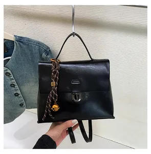 Details des schwarzen Lederrucksacks mit Metallverschluss und gewebtem Anhänger