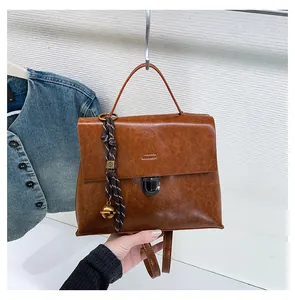 Details der braunen Vintage-Handtasche mit Metallverschluss und dekorativem Glockenanhänger
