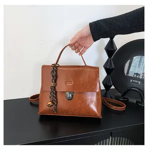 Detail der braunen Vintage-Ölledertasche mit Silberverschluss und geflochtenem Glocken-Anhänger