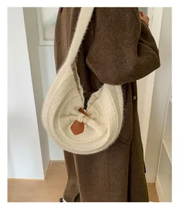 Detail of cream knit shoulder bag with rich texture and dark brown leather fastener