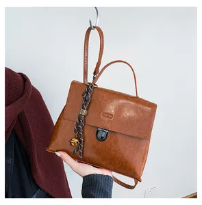Detail der braunen Vintage-Tasche mit Metallschnalle und gewebtem Glockenanhänger