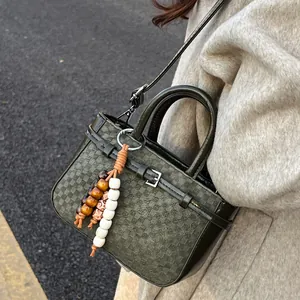 Elegant dark green vintage structured handbag with bohemian bead charm and crossbody strap