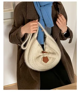 Close-up of knit hobo bag with toggle closure on brown wool coat and blue scarf