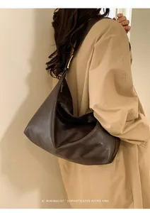 Vista laterale della borsa hobo in pelle testa di moro su modella in trench beige