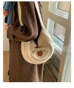 Detail of cream knit crescent bag with wooden horn buckle closure and vertical texture
