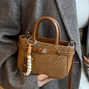 Brown vintage woven handbag with wooden bead charm worn over a grey plaid blazer