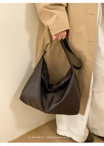 Dettaglio della borsa hobo marrone retrò minimalista con tracolla larga indossata