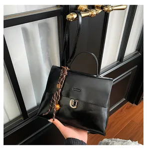 Detail der schwarzen Lackleder-Tasche mit Silberverschluss und dekorativem Anhänger