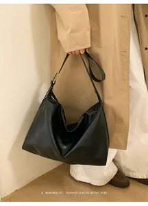 Dettaglio borsa Hobo nera in pelle con fibbia dorata minimalista sulla tracolla larga