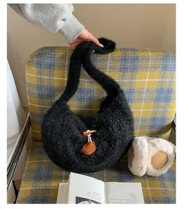 Detail of black faux fur hobo bag featuring a wooden horn buckle on a soft winter sofa